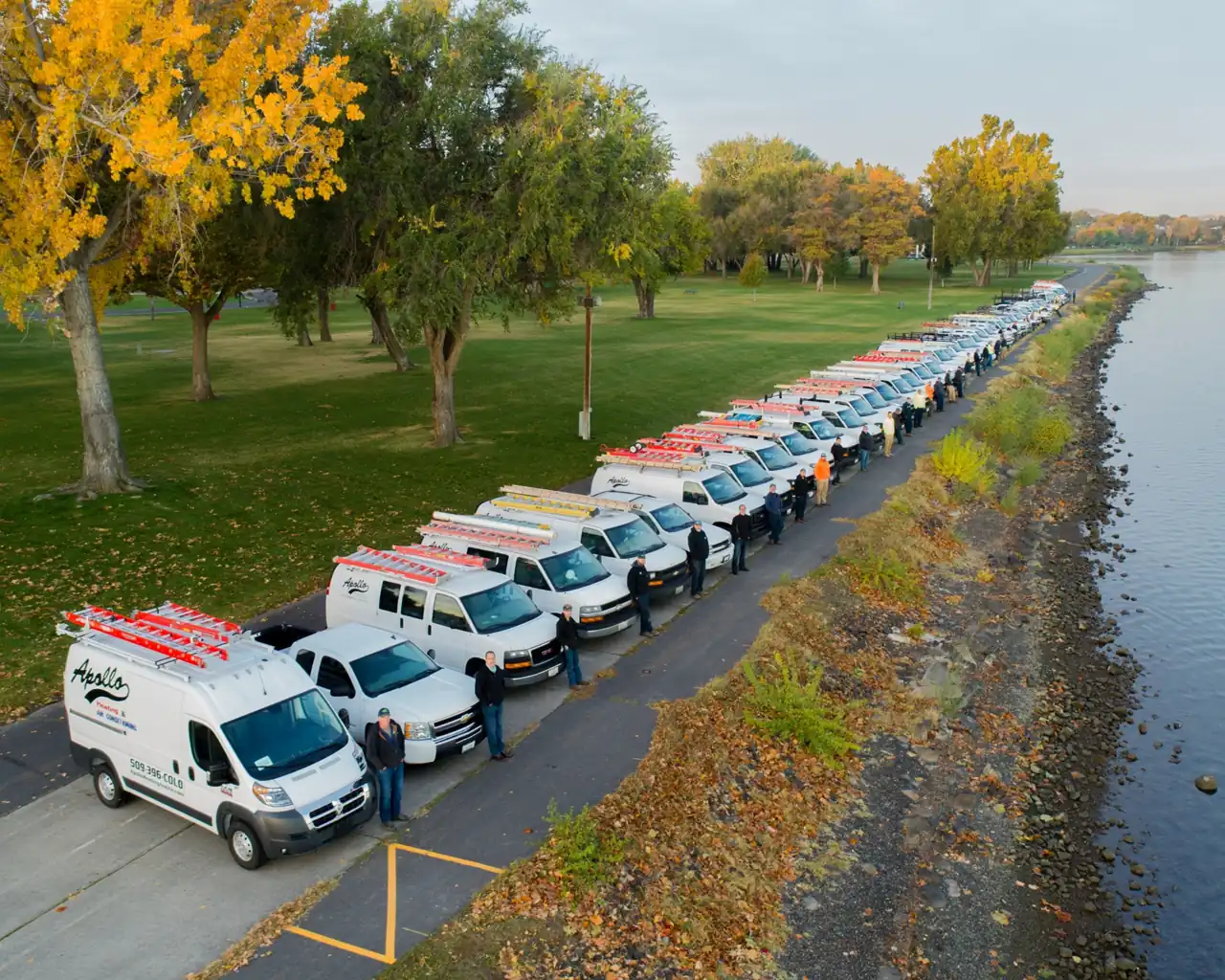 The Apollo fleet of white vans parked in a line along the Columbia River path