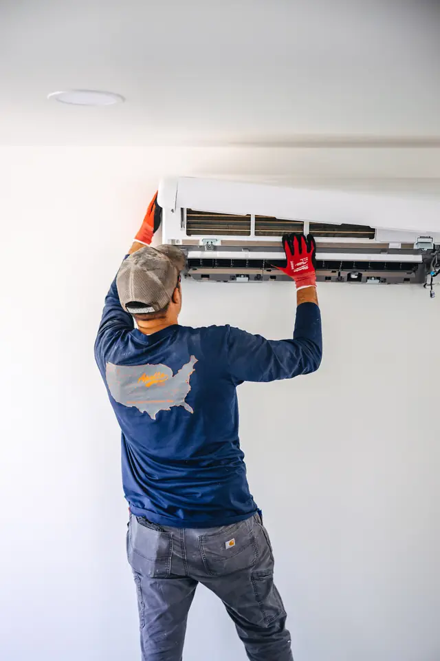 An Apollo installer mounting a ductless indoor head high on a white wall