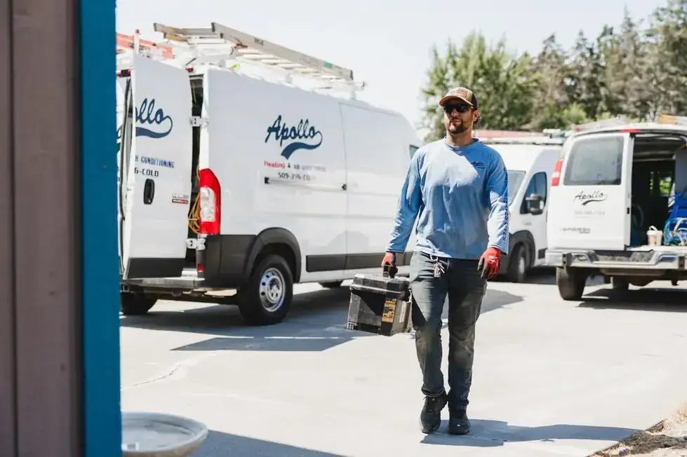 An Apollo technician carrying a toolbox between the company vans