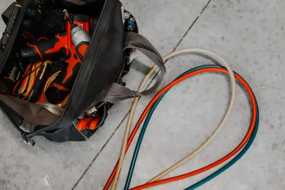 An open technician's tool bag with coiled refrigerant hoses on concrete